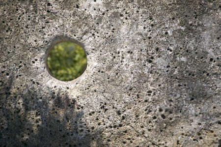 hole in ancient millstone, blurry green trees visible through holeの写真素材