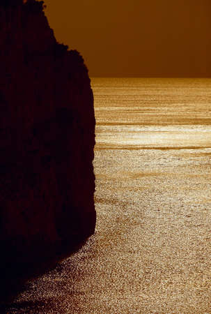 Sunset reflection in water, cliff full black with no detailsの写真素材