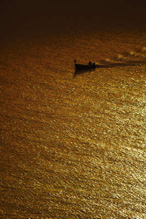 Boat in sunset visible in water, trails, rich yellow and orange color	の写真素材