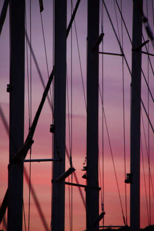 Sailboats masts with rich color sky in background	の写真素材