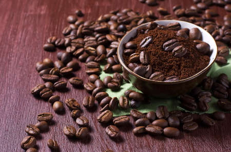 Bowl with coffee beans and ground coffee on a dark photoの写真素材