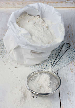Sack with flour and sieve on a light backgroundの写真素材