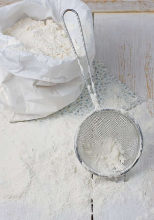 Sack with flour and sieve on a light backgroundの写真素材