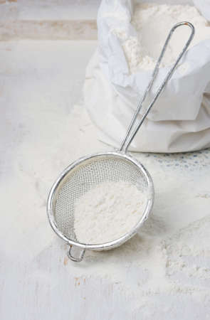 Sack with flour and sieve on a light backgroundの写真素材
