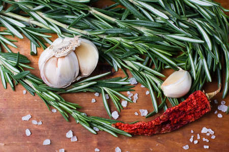 Fresh rosemary, garlic and hot peppers on old wooden backgroundの写真素材