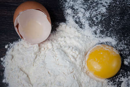 Flour and eggs on a wooden table, means for making breadの写真素材