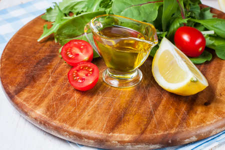 olive oil, lemon slice and fresh cherry tomatoes on a wooden boardの写真素材