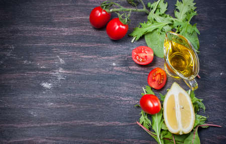 fresh cherry tomatoes, slices of lemon, lettuce and olive oil on a dark backgroundの写真素材