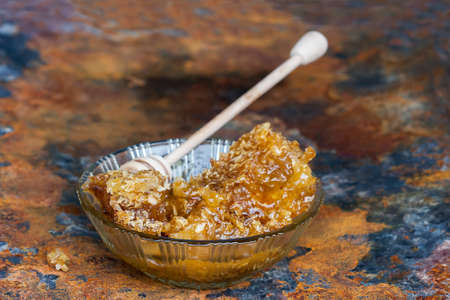 Honeycomb with  wooden honey dipper,  on dark old texture backgroundの写真素材