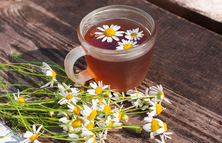 cup of chamomile tea with chamomile flowers, old wood table backgroundの写真素材