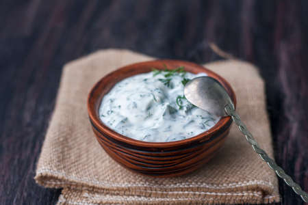 Bowl of fresh yogurt dip with dill and garlic on wooden background. selective Focusの写真素材