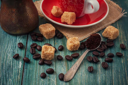 Red cup of coffee on wooden background, coffee beans and sugar on wooden board. Selective focusの写真素材