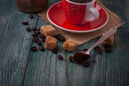 Red cup of coffee on wooden background, coffee beans and sugar on wooden board. Selective focusの写真素材