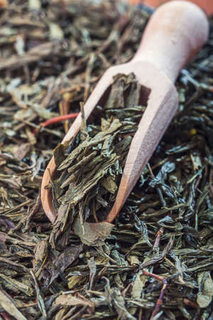 Spoon of dried green tea leaves on wooden background. Selective focusの写真素材