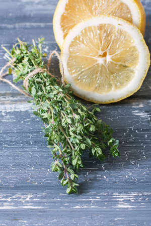 Bunch of fresh organic thyme and  lemon on a wooden  surface. Selective focusの写真素材