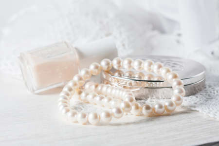 White pearl necklace, women's accessories, on handmade lace background. Selective focus.の写真素材
