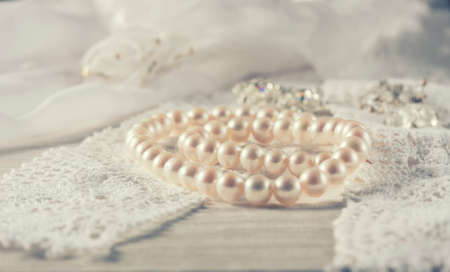 White pearl necklace on handmade lace background. Photo toned, selective focus.の写真素材