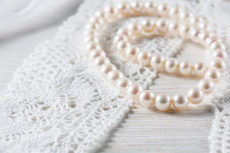 White pearl necklace on handmade lace background. selective focus.
