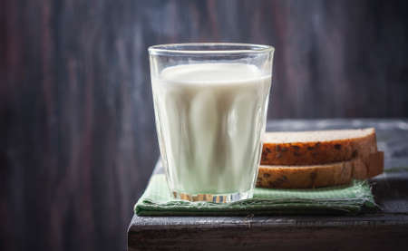 Glass of milk with  bread  on rustic wooden planks background. Selective focusの写真素材