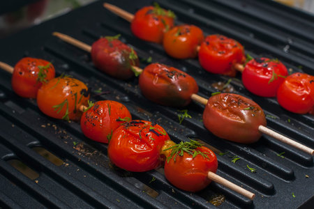 Grilled veggie skewers with cherry tomatoes with fresh dill on a grill. Selective focus