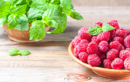 Ripe sweet raspberries in bowl on wooden table, closeup. Selective focus