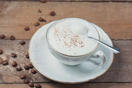 A cup of Capuchino coffee in a white cup, on wooden background.の写真素材