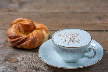 A cup of Capuchino coffee in a white cup, on wooden background.の写真素材