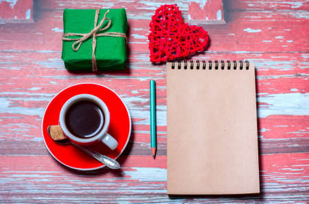 Notepad, cup of coffee, box with gift on a blue wooden table. Space for text, top viewの写真素材