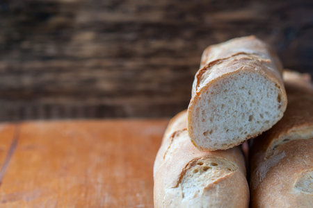Fresh baguette on wooden table, close up. Selective focus