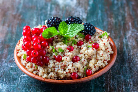Quinoa salad with berries, mint and walnuts on a dark wooden background. Superfoods and clean eating concept. Selective focus.の写真素材
