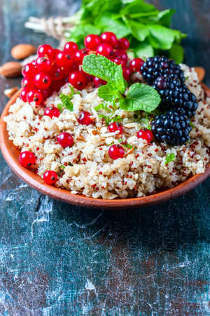 Quinoa salad with berries, mint and walnuts on a dark wooden background. Superfoods and clean eating concept. Selective focus.の写真素材