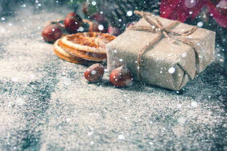 Gift box wrapped linen cloth and decorated with linen cord, jute, christmas decoration on brown vintage wooden boards background. Drawn Snowfall. Selective focusの写真素材