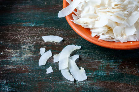Ceramic bowl with shredded coconut flakes on wooden background, superfood. Selective focusの写真素材