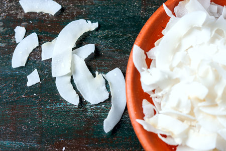 Ceramic bowl with shredded coconut flakes on wooden background, superfood. Selective focusの写真素材