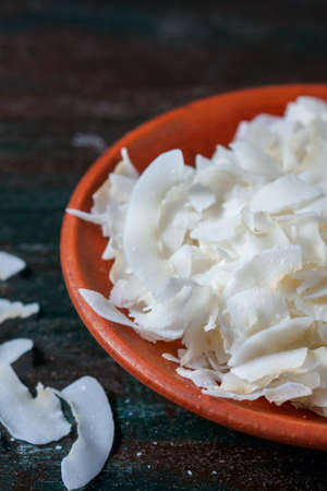Ceramic bowl with shredded coconut flakes on wooden background, superfood. Selective focusの写真素材