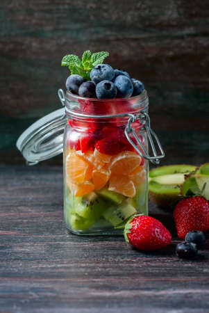 Healthy homemade fruit salad in a jar on rustic wooden background. Healthy food, Diet, Detox or Vegetarian concept. Selective focusの写真素材