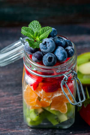 Healthy homemade fruit salad in a jar on rustic wooden background. Healthy food, Diet, Detox or Vegetarian concept. Selective focusの写真素材