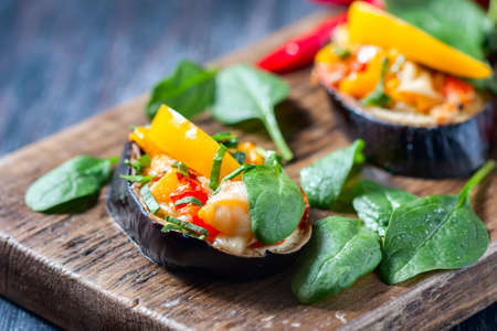 Baked stuffed eggplant with peppers, cheese and tomatoes on rustic wooden table, vegetarian food. Selective focusの写真素材