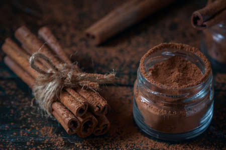 Cinnamon sticks and cinnamon powder close up on wooden background, rustic style, selective focusの写真素材