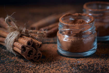 Cinnamon sticks and cinnamon powder close up on wooden background, rustic style, selective focusの写真素材