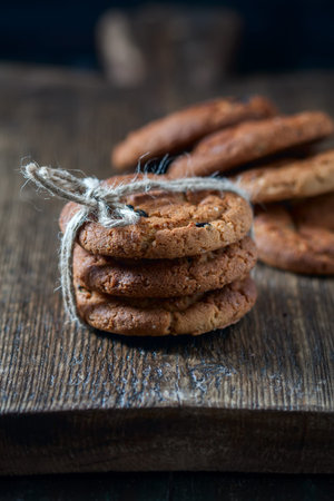 Oatmeal cookies with raisins, chocolate folded in a pile on the old table, wood background, selective focusの写真素材