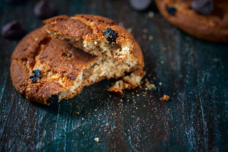 Oatmeal cookies with raisins, chocolate folded in a pile on the old table, wood background, selective focusの写真素材