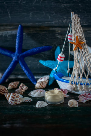 Handmade cosmetic cream and ship with shells. Spa setting on wooden table background, selective...
