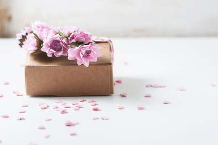 Kraft box and pink roses on white table, concept of Valentines Day, holiday. Selective focus. Red heart.の写真素材