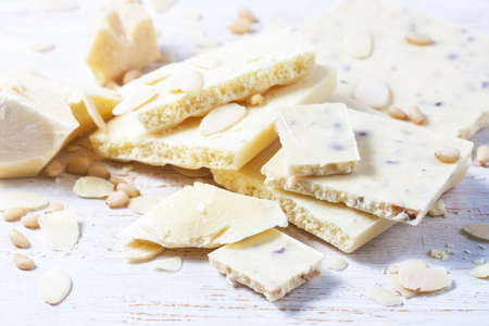 White chocolate pieces with nuts on a white wood background. Selective focusの写真素材