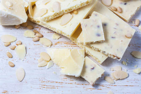 White chocolate pieces with nuts on a white wood background. Selective focusの写真素材