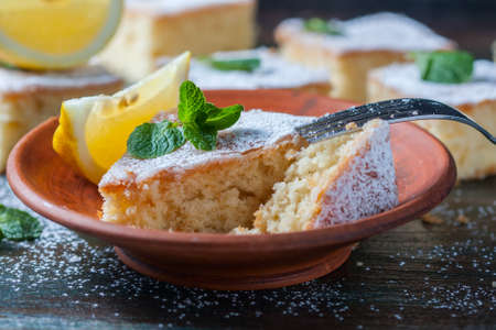 Fresh homemade sweet cake for breakfast with slices of lemon and mint on wooden board. Selective Focusの写真素材