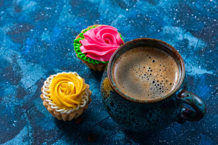 offee in blue cup, and delicious cakes on dark blue backgroundの写真素材