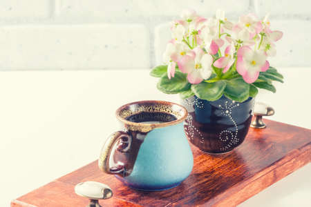 Cup of black coffee with croissant, Pink and White African Violet on white table. Selective focusの写真素材