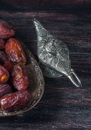 Dates and silver aladdin's lamp on a dark wooden background. Ramadan concept. Selective focusの写真素材